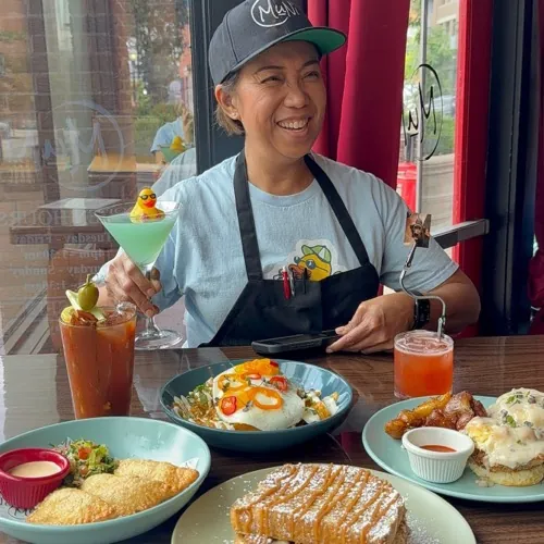 MuNi KC chef smiling at a brunch table loaded with French toast, chilaquiles, and cocktails